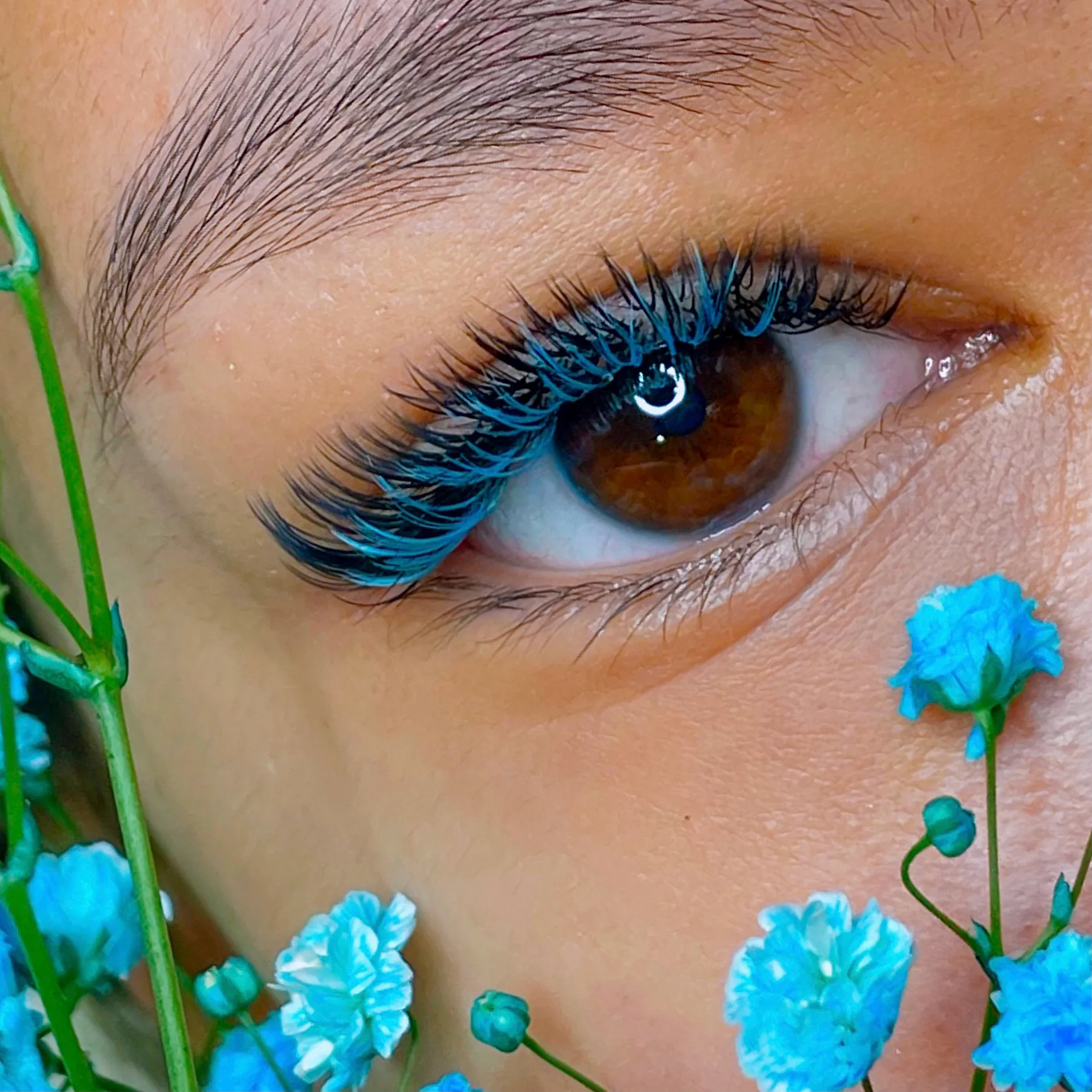 Close view of a client's eye with bright blue lash accents.