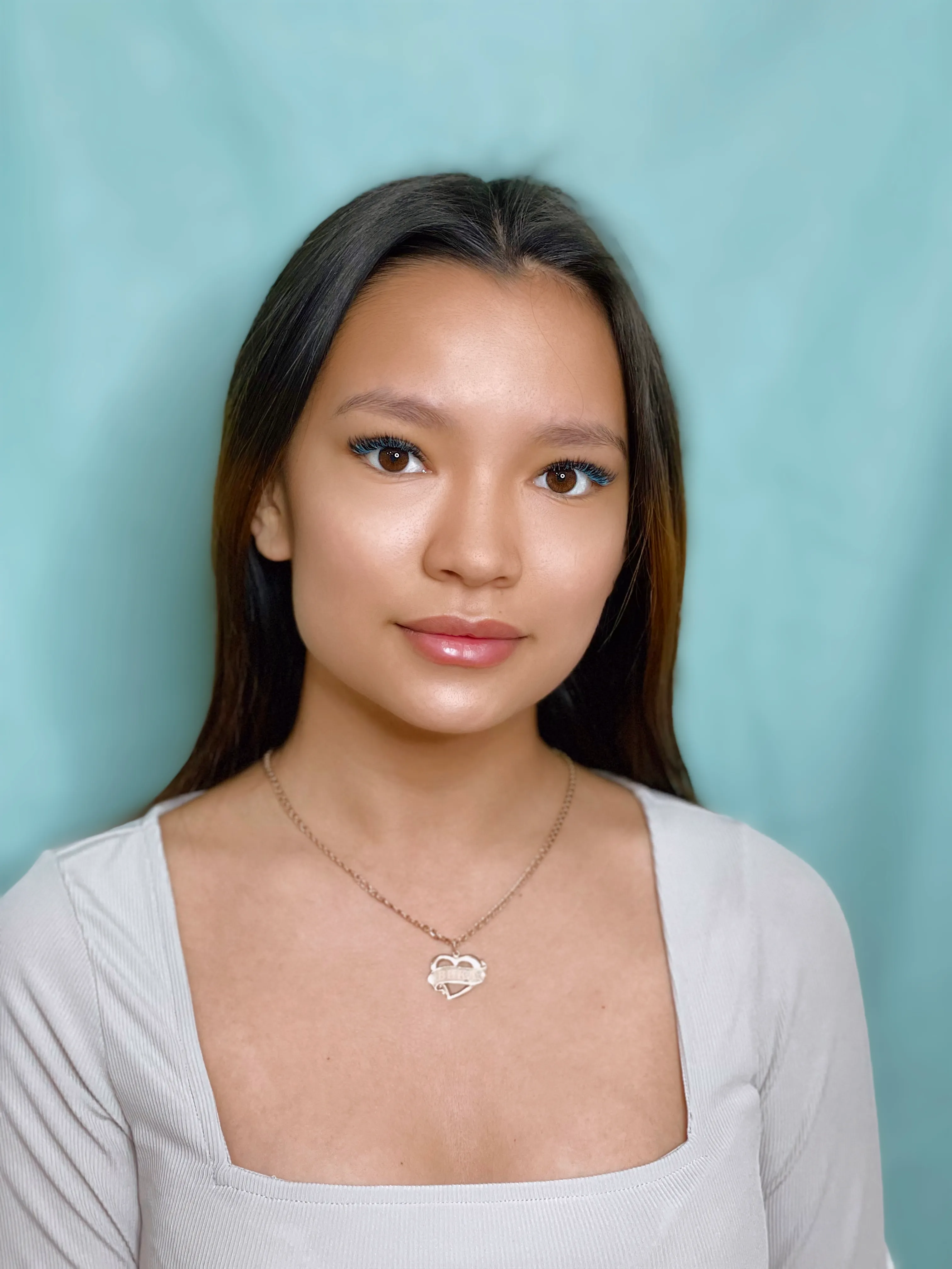 Portrait of a woman with blue lash accents against a blue background.