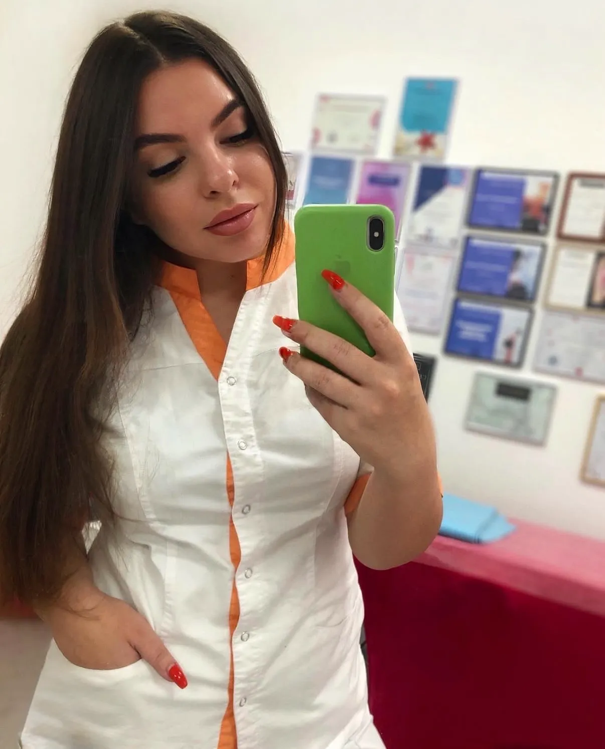 Mirror portrait of a woman in a white and orange uniform.